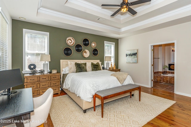 bedroom featuring crown molding, ceiling fan, baseboards, a tray ceiling, and wood finished floors