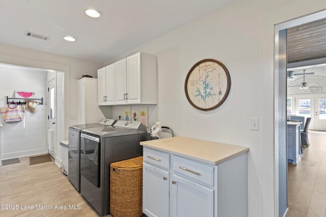 clothes washing area featuring light wood finished floors, visible vents, cabinet space, and separate washer and dryer