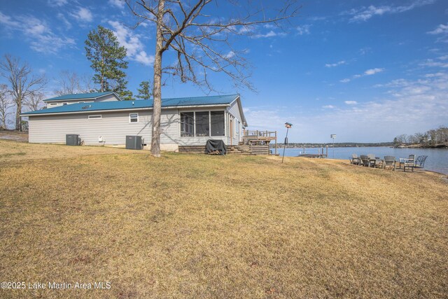 exterior space featuring a yard, a water view, central AC unit, and metal roof