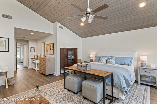 bedroom with lofted ceiling, crown molding, wood finished floors, and visible vents