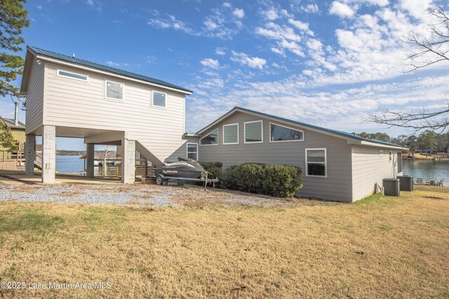 rear view of house with a water view, a yard, gravel driveway, a carport, and stairs