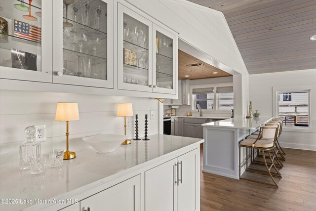 bar featuring vaulted ceiling, a healthy amount of sunlight, dark wood-type flooring, and wooden ceiling