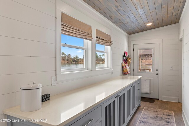 interior space with lofted ceiling, wood ceiling, wood walls, and light countertops