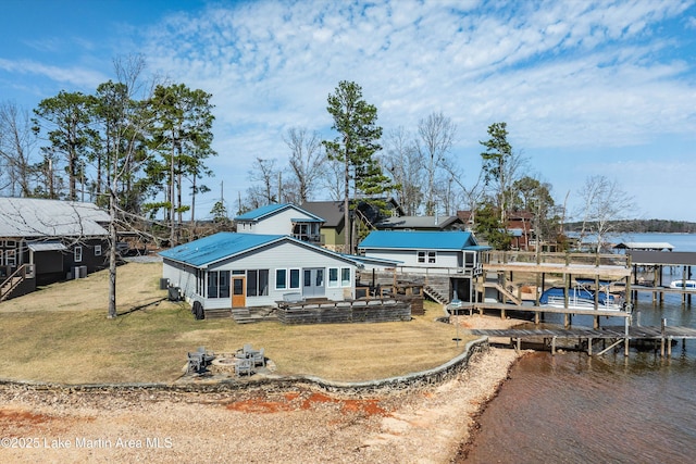 rear view of property featuring a fire pit, a water view, entry steps, a lawn, and a sunroom