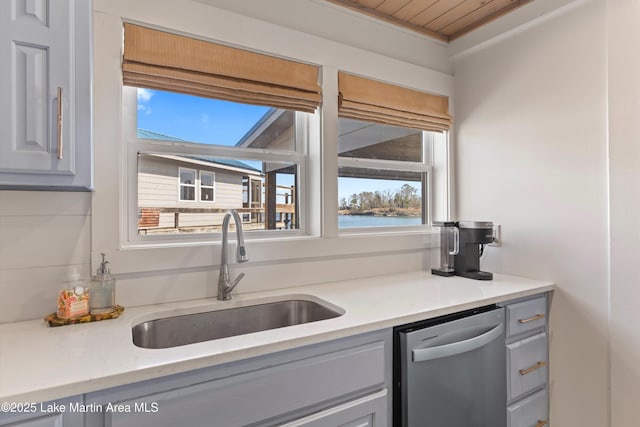 kitchen featuring a sink, a water view, dishwasher, and light countertops