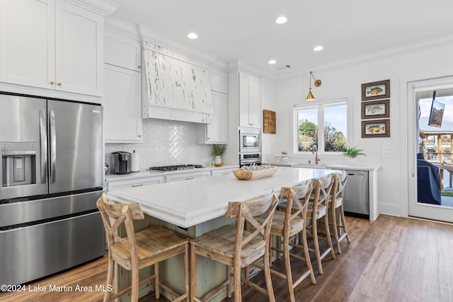 kitchen with a breakfast bar, stainless steel appliances, a kitchen island, and white cabinetry