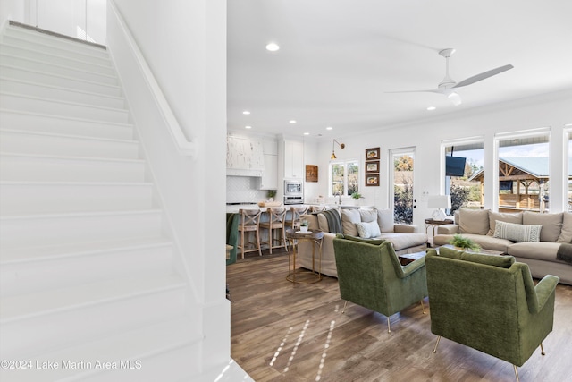 living room with hardwood / wood-style flooring, ceiling fan, and ornamental molding