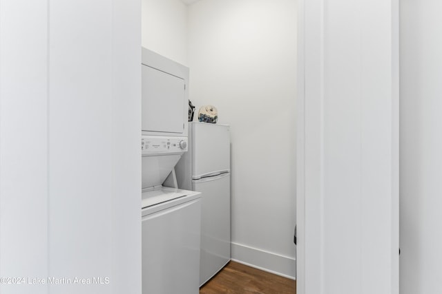 clothes washing area featuring dark hardwood / wood-style floors and stacked washer and dryer