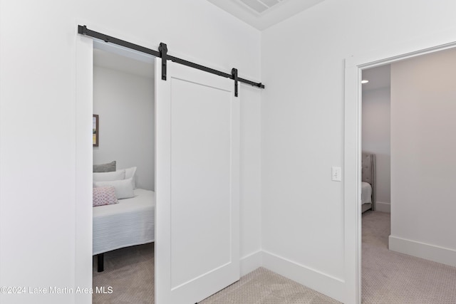 interior space with a barn door and light colored carpet