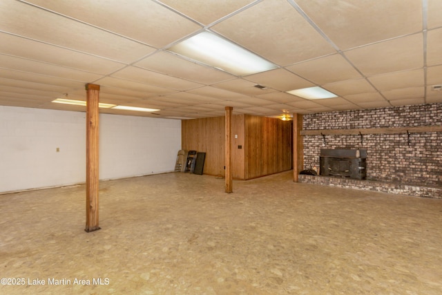 basement with a paneled ceiling and a wood stove