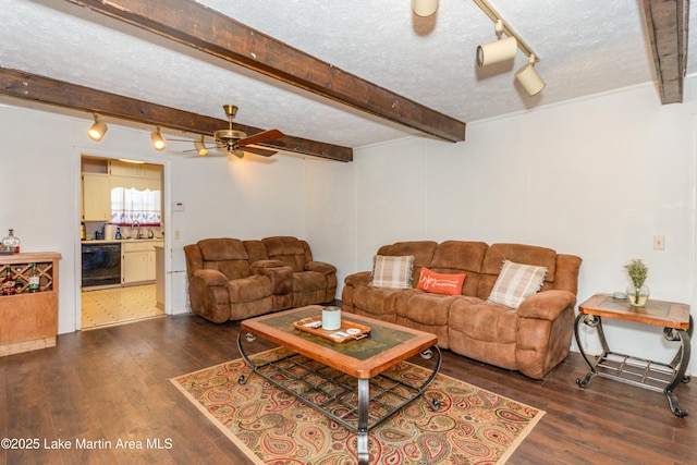 living room with ceiling fan, a textured ceiling, dark hardwood / wood-style flooring, and beamed ceiling