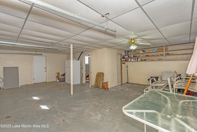 basement with ceiling fan, a paneled ceiling, and white fridge