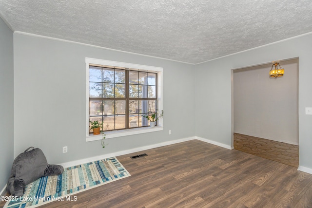 unfurnished room featuring dark hardwood / wood-style floors, ornamental molding, and a textured ceiling