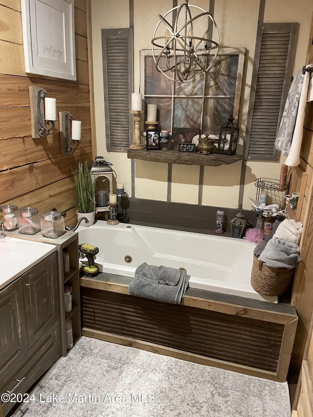 bathroom with a bathing tub, vanity, wooden walls, and a notable chandelier