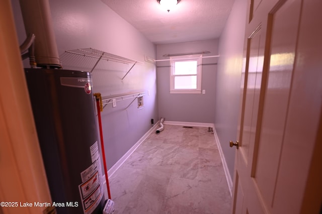 clothes washing area featuring hookup for a washing machine, water heater, laundry area, baseboards, and a textured ceiling