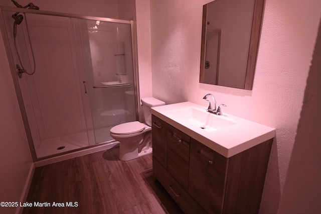 bathroom featuring a stall shower, wood finished floors, a textured wall, and vanity
