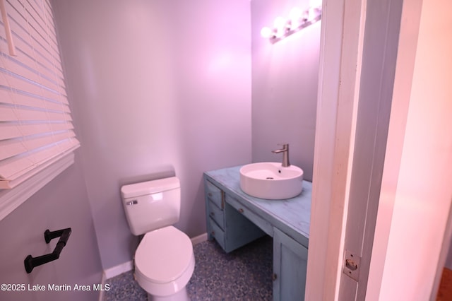 bathroom featuring toilet, vanity, and baseboards