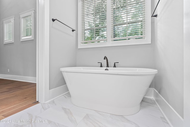 bathroom featuring hardwood / wood-style flooring and a tub to relax in