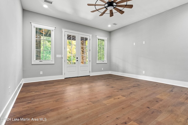 empty room with ceiling fan, hardwood / wood-style floors, and french doors