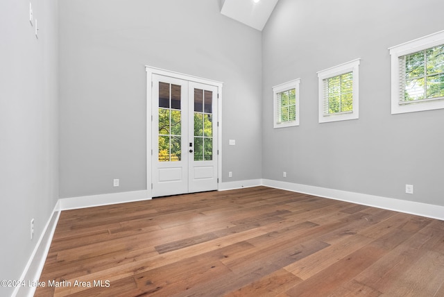 unfurnished room featuring wood-type flooring, a high ceiling, and french doors