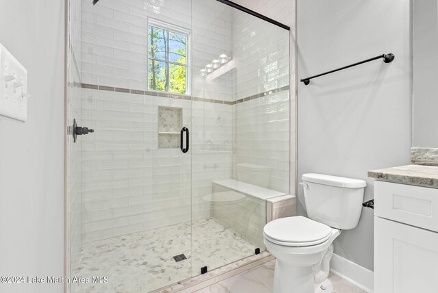 bathroom featuring vanity, a shower with shower door, and toilet