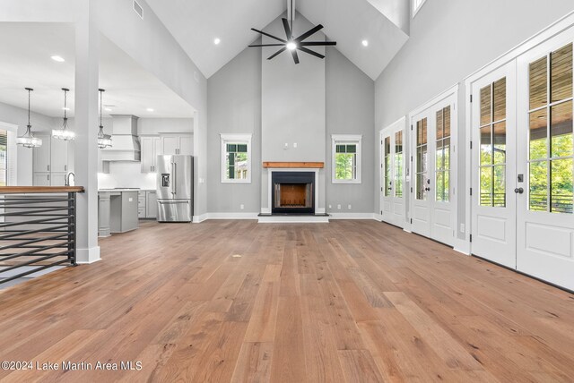 unfurnished living room featuring plenty of natural light, light wood-type flooring, and high vaulted ceiling