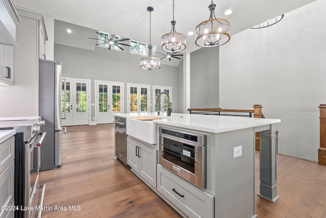 kitchen featuring stainless steel appliances, a kitchen breakfast bar, pendant lighting, light hardwood / wood-style floors, and a kitchen island with sink