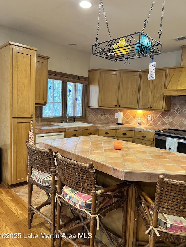 kitchen featuring sink, decorative backsplash, stainless steel electric stove, and tile countertops