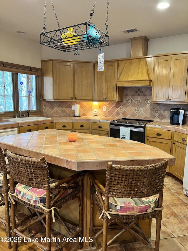 kitchen featuring a kitchen island, sink, tile countertops, and stainless steel electric range