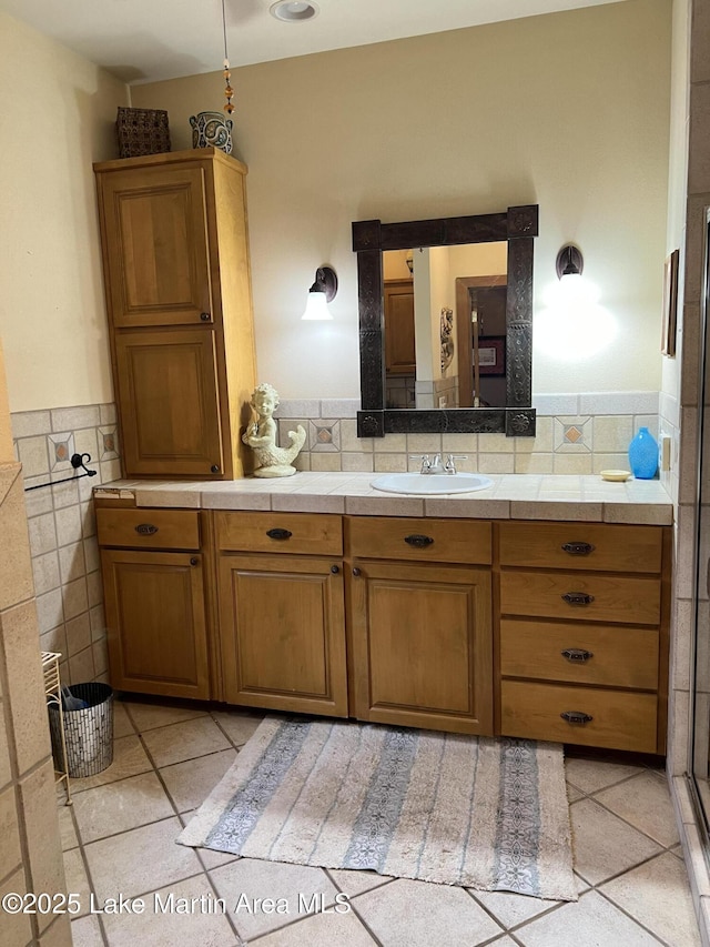 bathroom featuring walk in shower, vanity, and tile walls