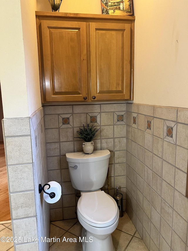 bathroom with tile patterned flooring, tile walls, and toilet