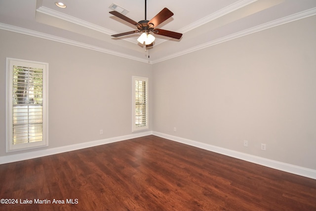 empty room with a raised ceiling, ceiling fan, dark hardwood / wood-style flooring, and ornamental molding