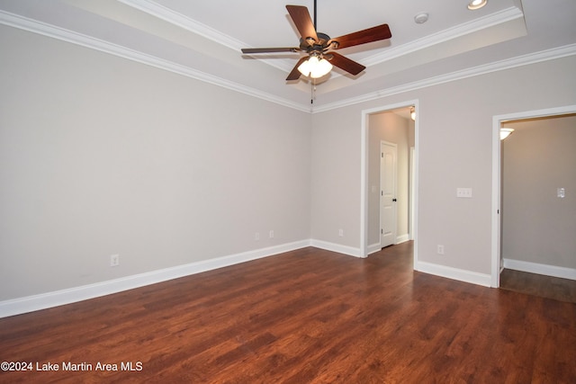 spare room featuring ceiling fan, crown molding, a tray ceiling, and dark wood-type flooring