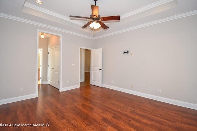 unfurnished bedroom featuring a raised ceiling, ceiling fan, dark hardwood / wood-style floors, and ornamental molding