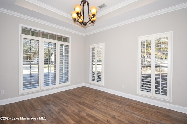 empty room featuring a raised ceiling, dark hardwood / wood-style flooring, an inviting chandelier, and ornamental molding