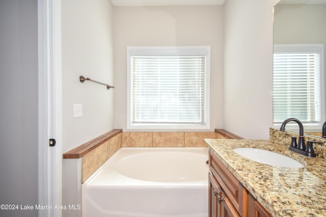 bathroom with a wealth of natural light, a bathtub, and vanity