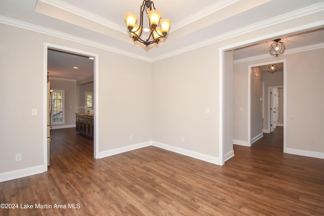 empty room with dark hardwood / wood-style floors, ornamental molding, and an inviting chandelier