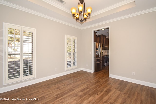 spare room with a raised ceiling, crown molding, dark wood-type flooring, and a notable chandelier