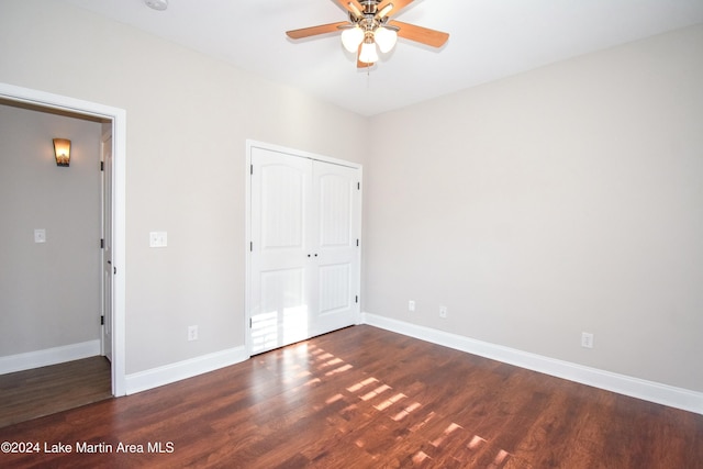 unfurnished bedroom featuring ceiling fan, a closet, and dark wood-type flooring