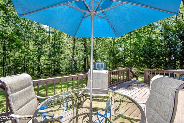 838 Bama Park Rd, Dadeville, AL 36853 - wooden deck featuring outdoor dining space, a storage unit, an outbuilding, a yard, and view of scattered trees