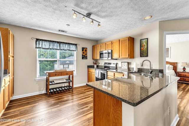 741 Lakeview Rdg, Dadeville, AL 36853 - kitchen with appliances with stainless steel finishes, a peninsula, wood finished floors, a textured ceiling, and dark stone counters