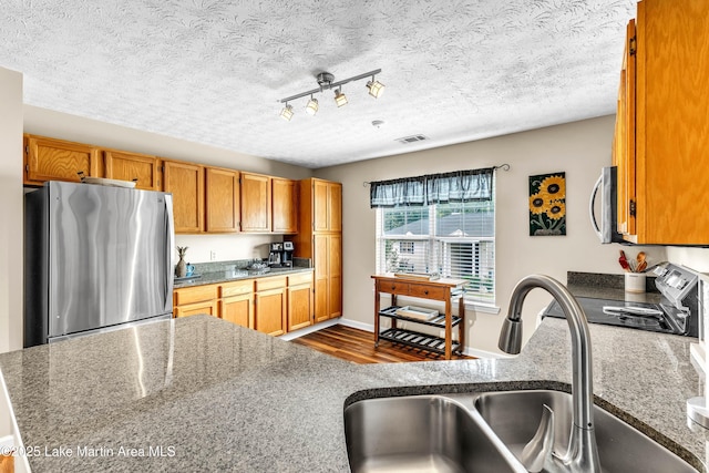 741 Lakeview Rdg, Dadeville, AL 36853 - kitchen with appliances with stainless steel finishes, dark wood finished floors, brown cabinets, a textured ceiling, and stone countertops