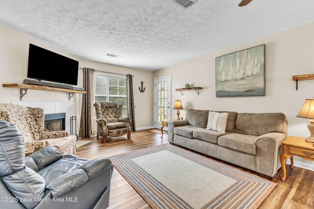 741 Lakeview Rdg, Dadeville, AL 36853 - living room featuring light wood-type flooring, a tiled fireplace, and a textured ceiling
