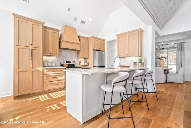 kitchen with light brown cabinetry, custom range hood, stainless steel appliances, sink, and high vaulted ceiling