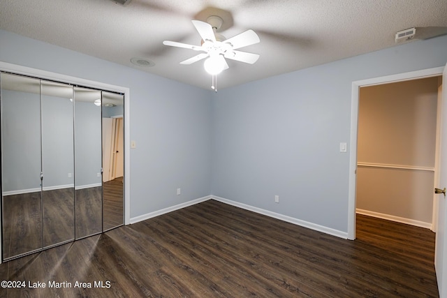 unfurnished bedroom with dark hardwood / wood-style flooring, ceiling fan, a closet, and a textured ceiling