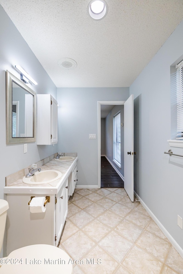 bathroom with vanity, toilet, and a textured ceiling