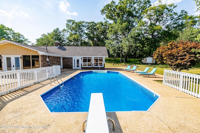 view of swimming pool with a storage shed, a diving board, a patio area, and french doors