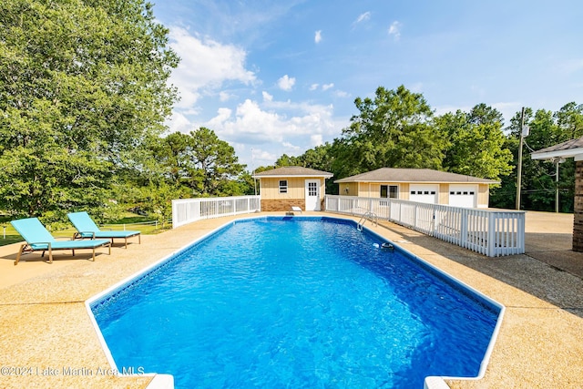 view of swimming pool with a garage, a patio, and an outbuilding