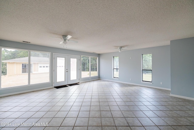 tiled spare room with a wealth of natural light, a textured ceiling, ceiling fan, and french doors