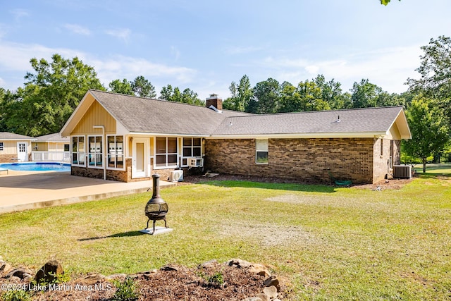 view of front of home featuring a patio area, central AC, a front lawn, and an outdoor fire pit